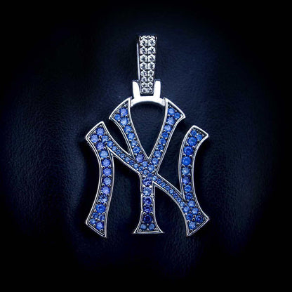 New York Yankees MLB logo pendant in 14k white gold plating with natural blue gemstones laid flat on textured surface.